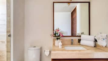 Een badkamer met een houten wastafelmeubel, een wastafel, een toilet en een spiegel.