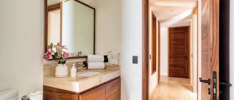Un baño moderno con tocador de madera, un espejo grande y un florero con flores.