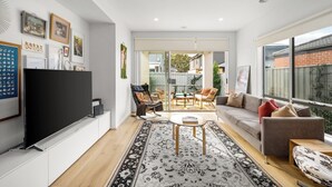 Ein modernes Wohnzimmer mit Flachbildfernseher, einer Couch, einem Couchtisch und einem gemusterten Teppich.