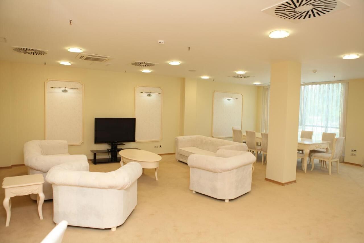 A spacious living room with a flat-screen TV, two sofas, a coffee table, and a dining area with chairs and a table.
