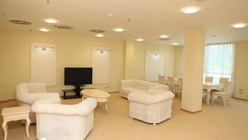 A spacious living room with a flat-screen TV, two sofas, a coffee table, and a dining area with chairs and a table.