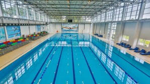 An indoor swimming pool with clear lanes, a high ceiling, and large windows. - Arena Hotel Kur (Mingacevir)