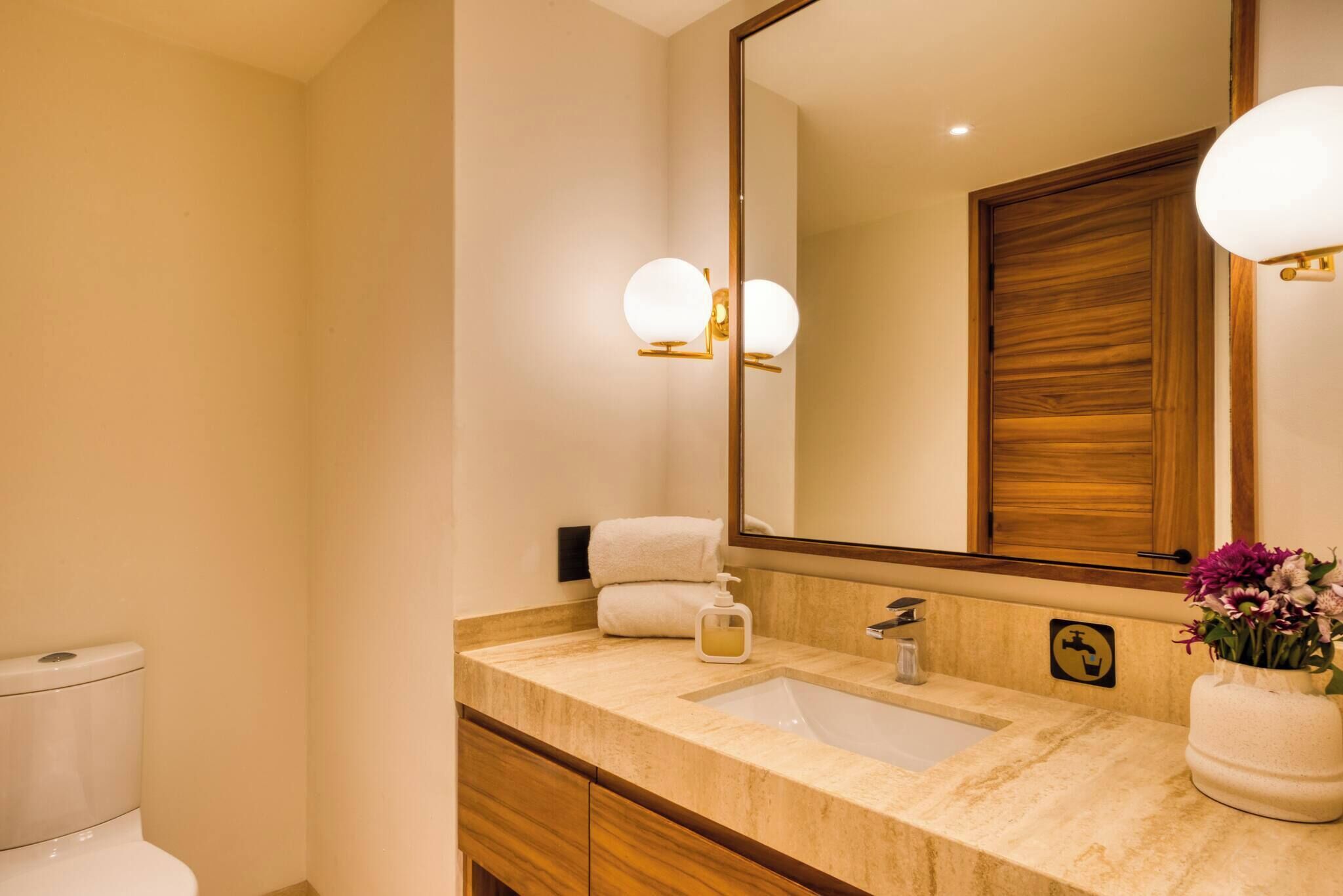 A bathroom with a marble sink, a large mirror, and a towel rack.