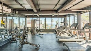 Une salle de sport équipée de tapis de course, d’appareils de musculation et de poids libres.