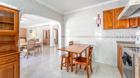 Una cocina moderna con armarios de madera, un comedor con mesa y sillas, y un salpicadero de azulejos.