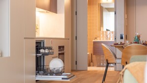 Una cocina compacta con lavavajillas, un comedor con mesa y sillas de madera, y salpicadero de azulejos.