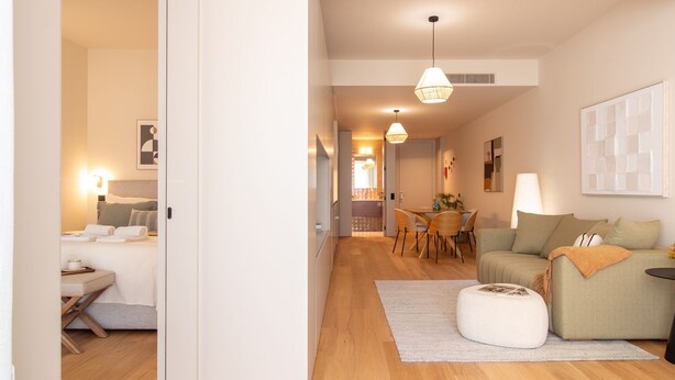 Una sala moderna con sofá, reposapiés y comedor con sillas y una mesa.