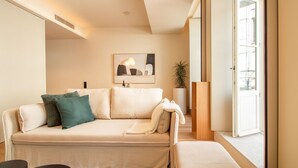 A modern living room with a beige sofa, a coffee table, and a potted plant. - Catarina 392 | Chic Studio by LovelyStay (Porto)