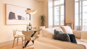 A modern living room with a sofa, a glass table, a chair, a potted plant, and a painting on the wall. - Catarina 392 | Chic Studio by LovelyStay (Porto)