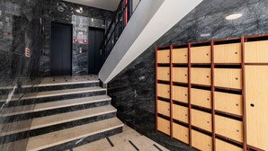 Eine moderne Treppe mit Marmorstufen und ein Holzbereich mit nummerierten Schließfächern.