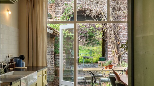 Una cocina con vistas a un jardín a través de un ventanal.