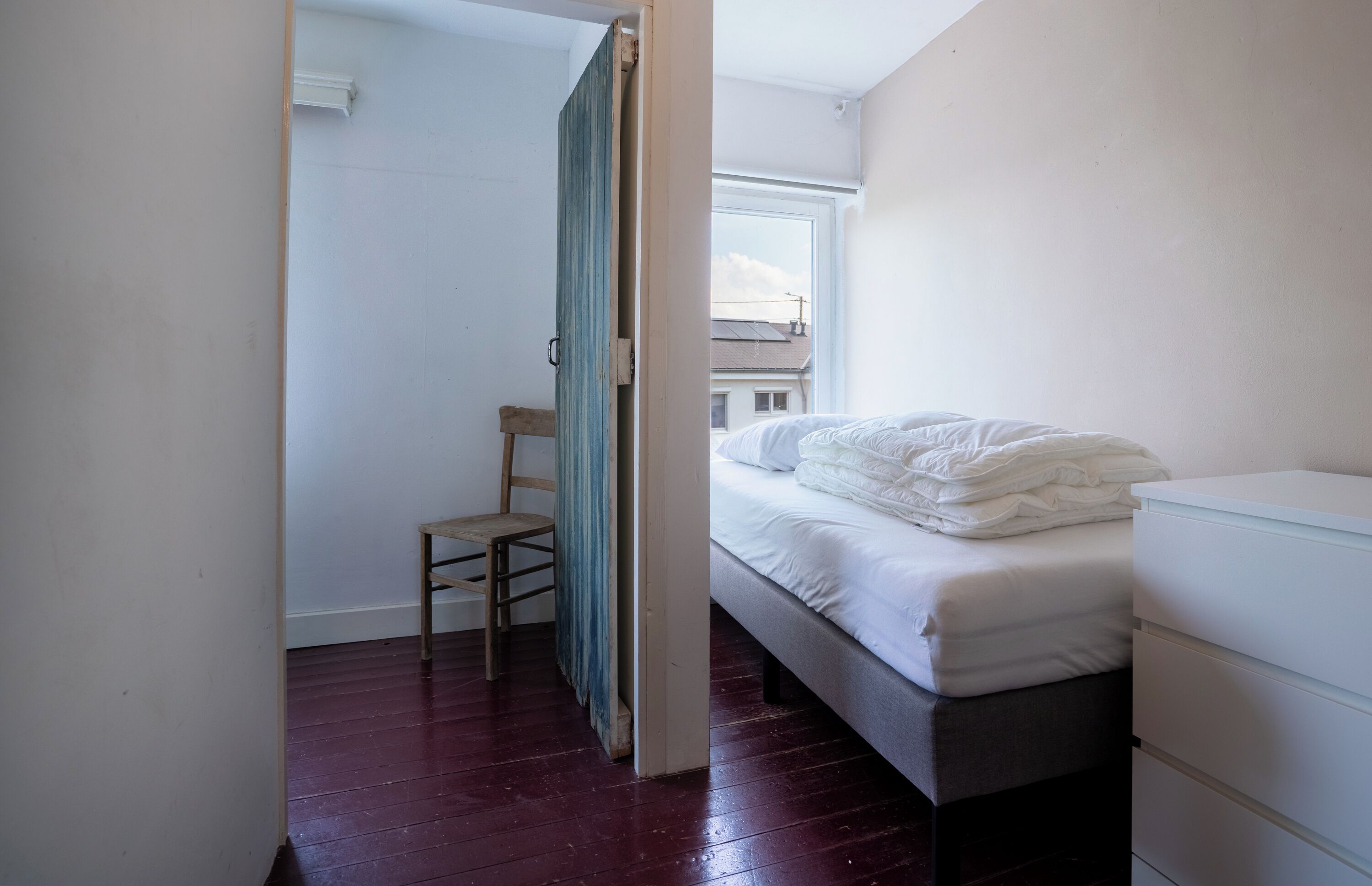 A bedroom with a bed, a chair, and a dresser.