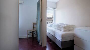 A bedroom with a bed, a chair, and a dresser.
