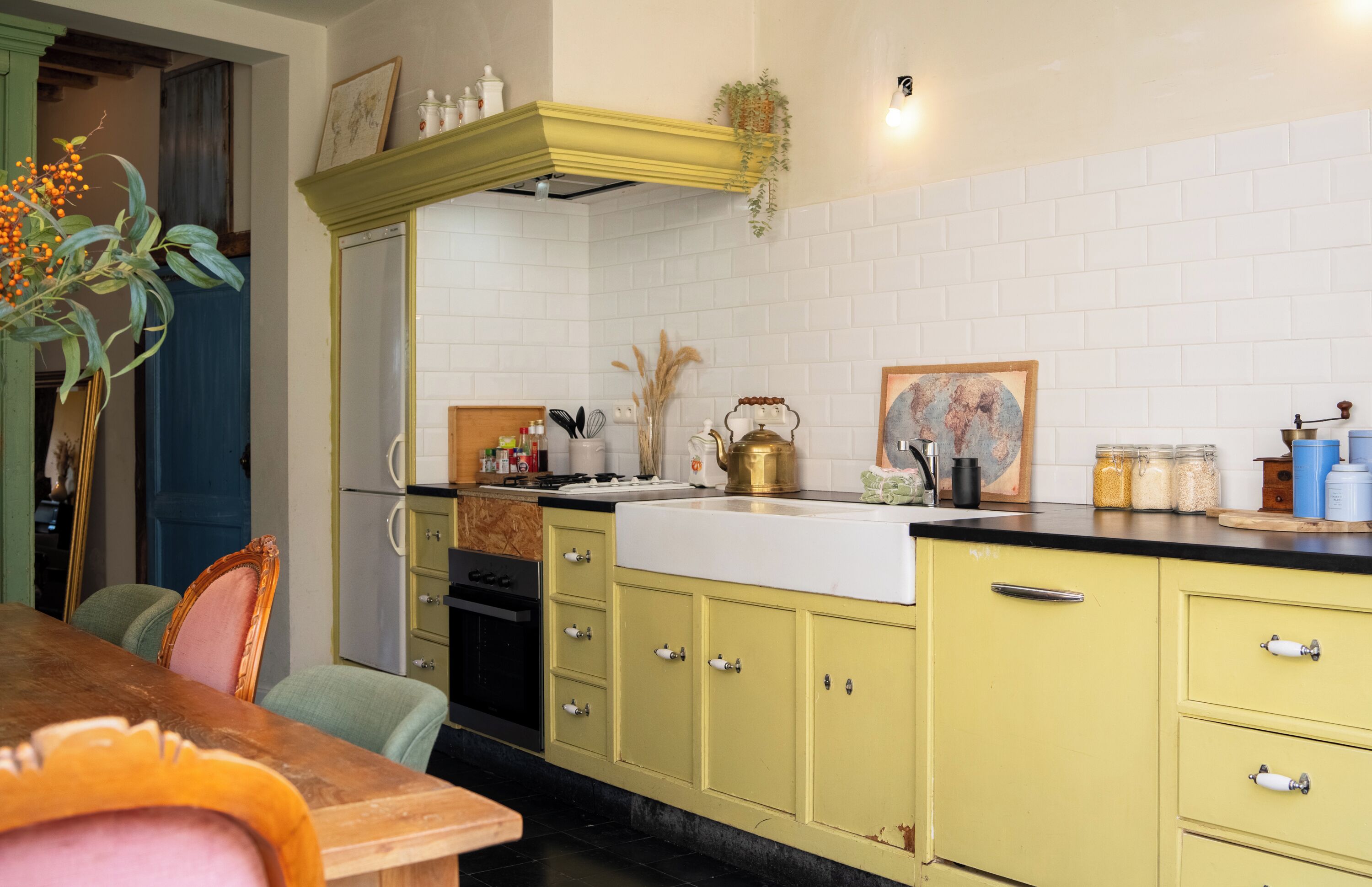 A kitchen with yellow cabinets, a white countertop, and a green chair.