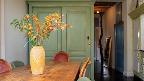 Una mesa de comedor con un jarrón de flores, una puerta verde y un pasillo con un espejo y armarios.