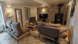 Uma sala de estar com lareira de pedra, televisão e sofá.