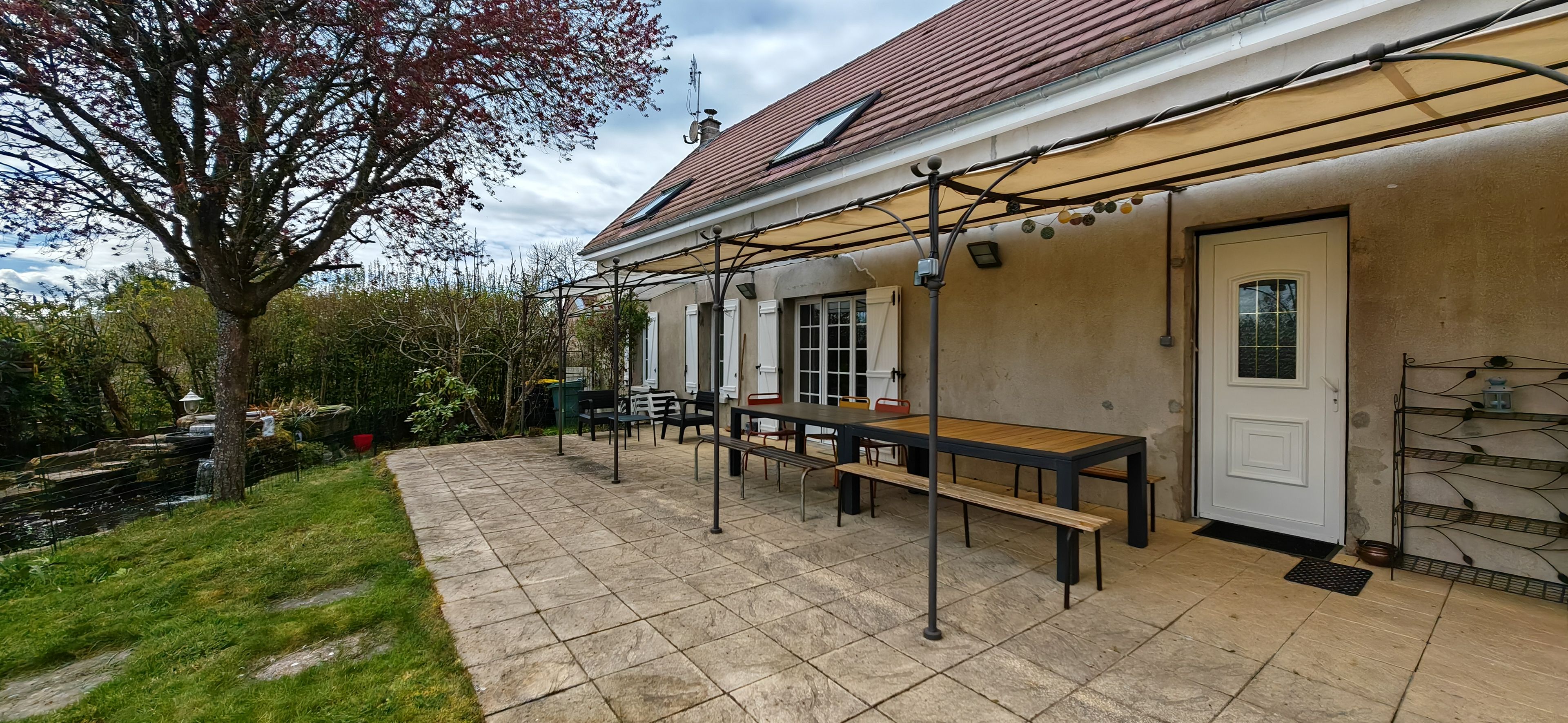 A patio with a table and benches, a door, and a small garden area.