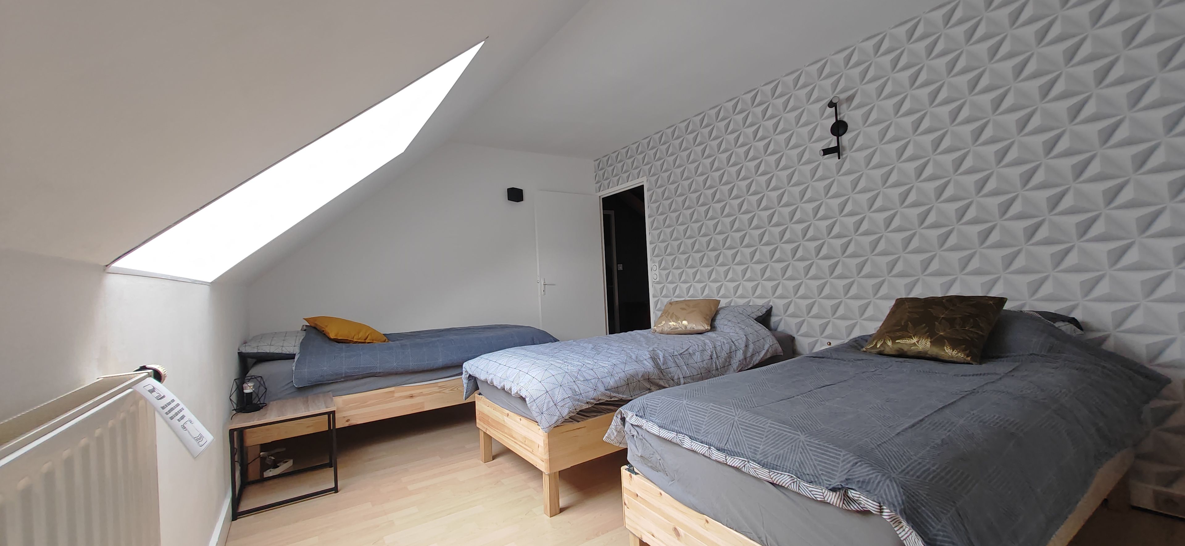Ein Zimmer mit zwei Betten, einem Oberlicht und einer Wand mit geometrischem Muster.