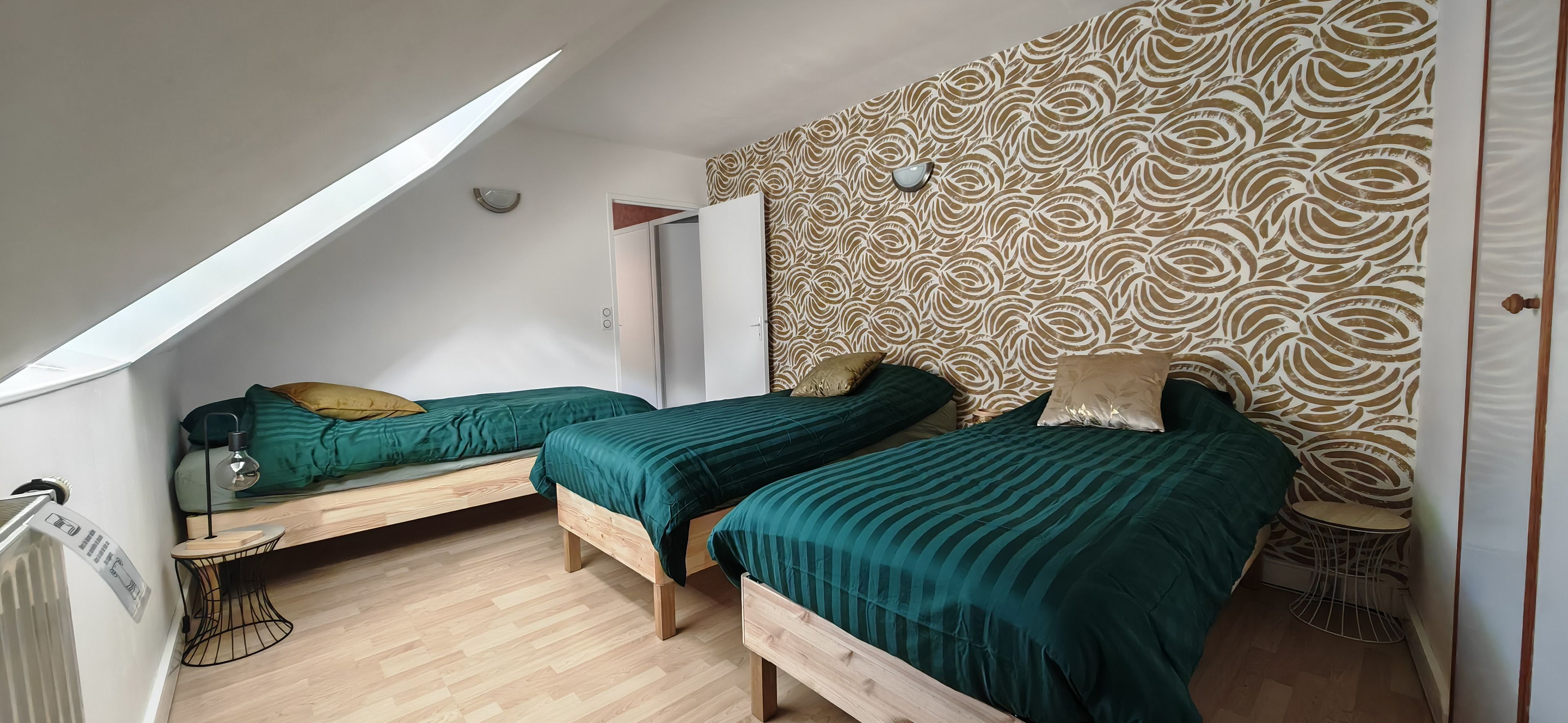 Une chambre avec deux lits, un radiateur, une petite table et un mur décoré de motifs.