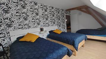 Un dormitorio con dos camas, un papel tapiz estampado y un techo inclinado.
