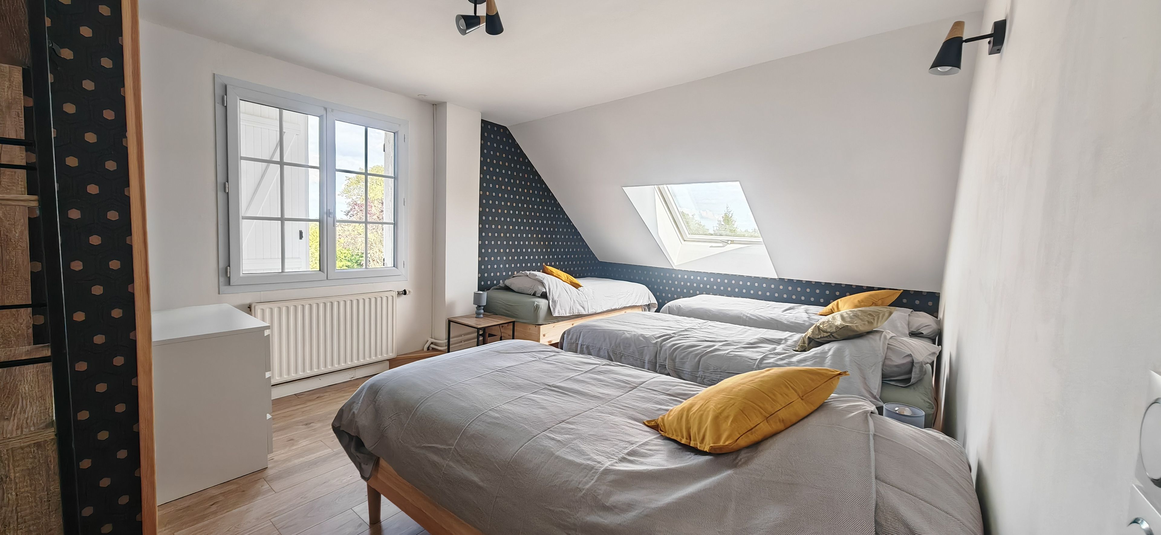 A bedroom with two beds, a window, a radiator, and a ceiling light fixture.