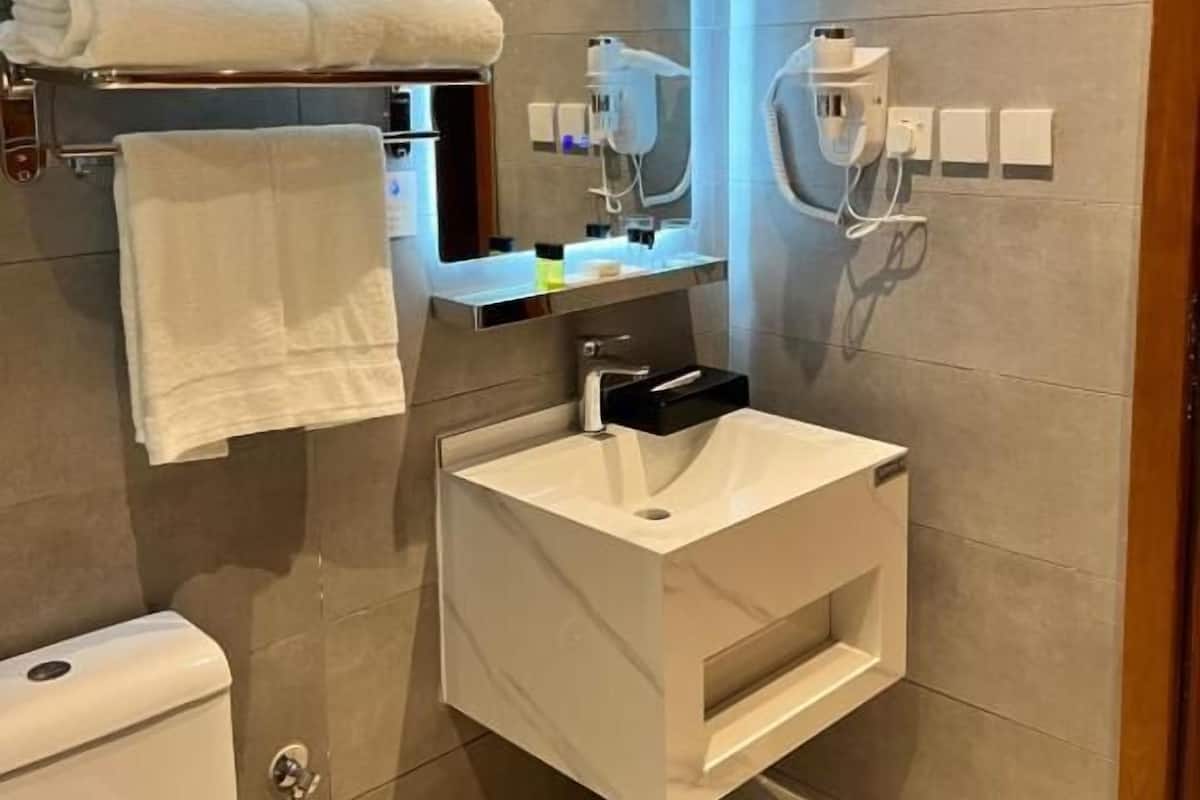 A modern bathroom with a white sink, a mirror, and a towel rack.