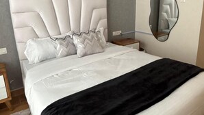 A modern bedroom with a large bed, a headboard, a bedside table, and a wall-mounted mirror. - Chic studio with WiFi and AC in serene Nairobi (Nairobi)