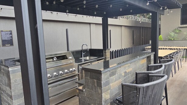 An outdoor bar area with a stone counter, bar stools, and a grill. - Chic studio with WiFi and AC in serene Nairobi (Nairobi)