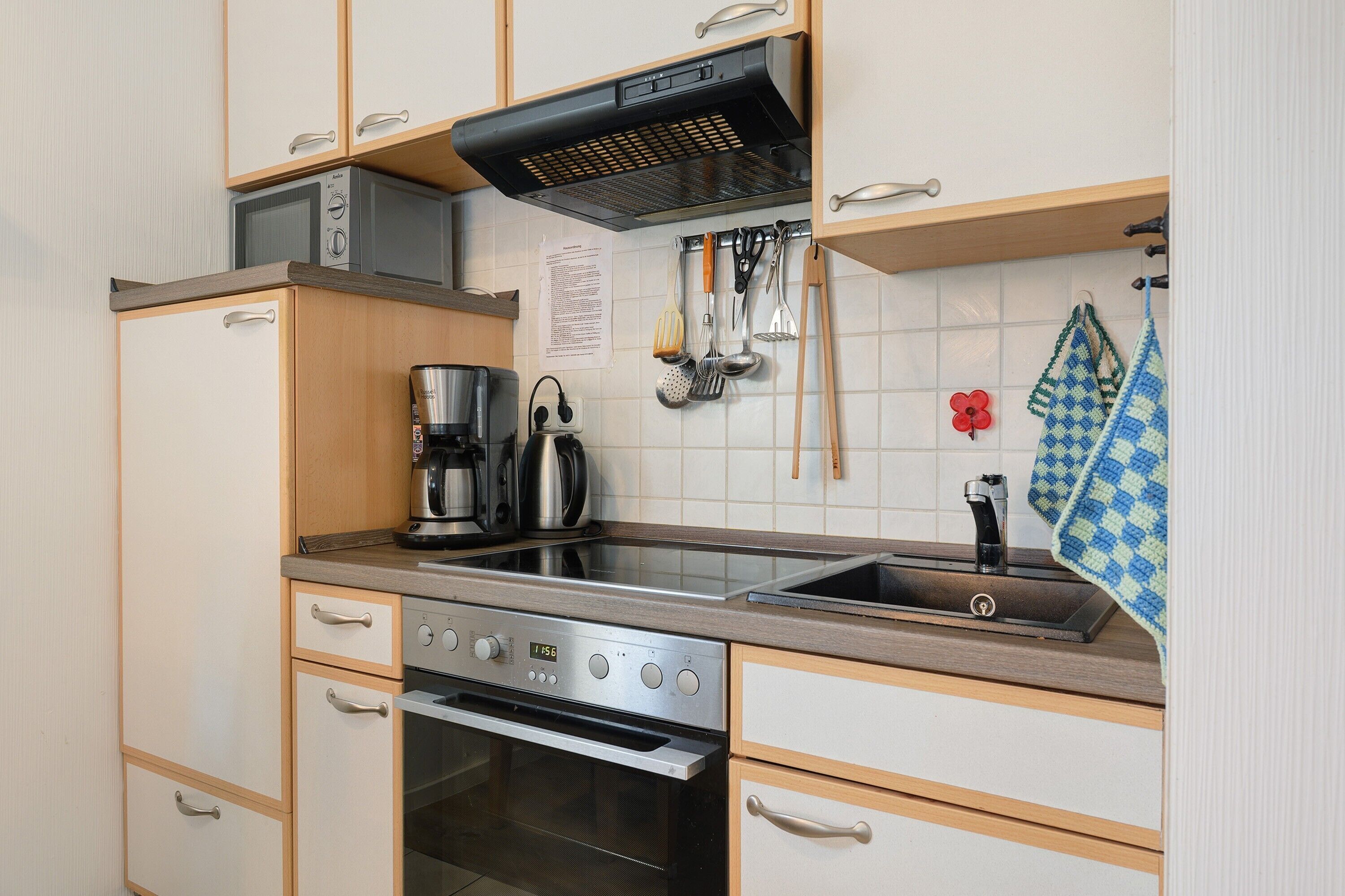 Uma cozinha compacta com fogão, forno, micro-ondas e cafeteira.