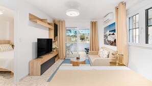 Quarto de hotel moderno com cama, televisão, sofá e varanda com vista.
