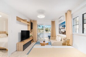 Une chambre d’hôtel moderne équipée d’un lit, d’une télévision, d’un canapé et d’un balcon avec vue.