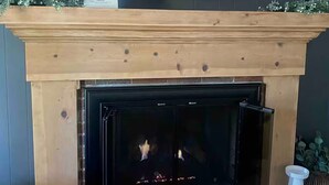 A fireplace with a TV above it, candles, and a sign.