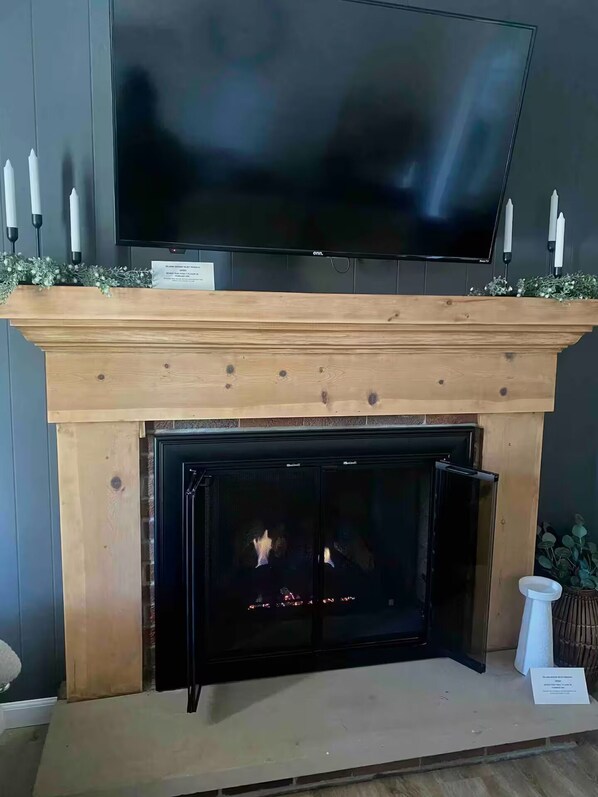 A fireplace with a TV above it, candles, and a sign.