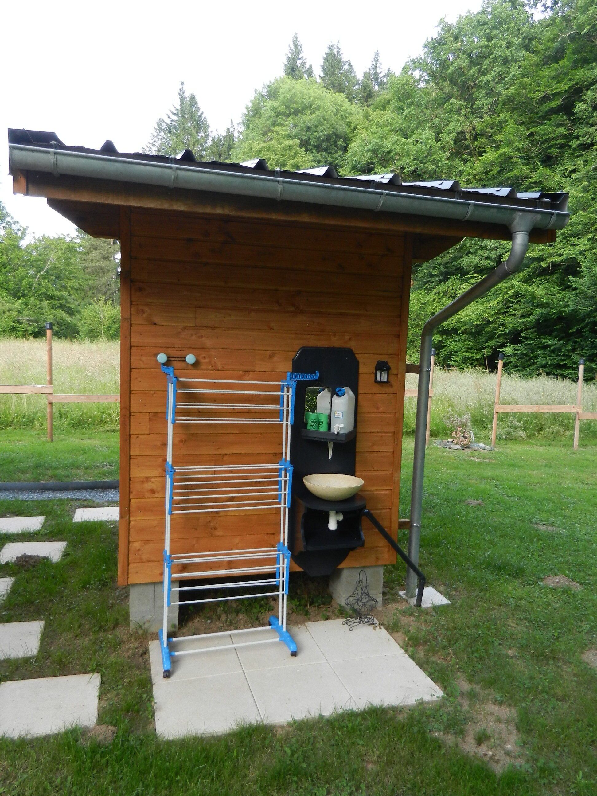 A small wooden cabin with a metal drying rack, a sink, and a water dispenser.
