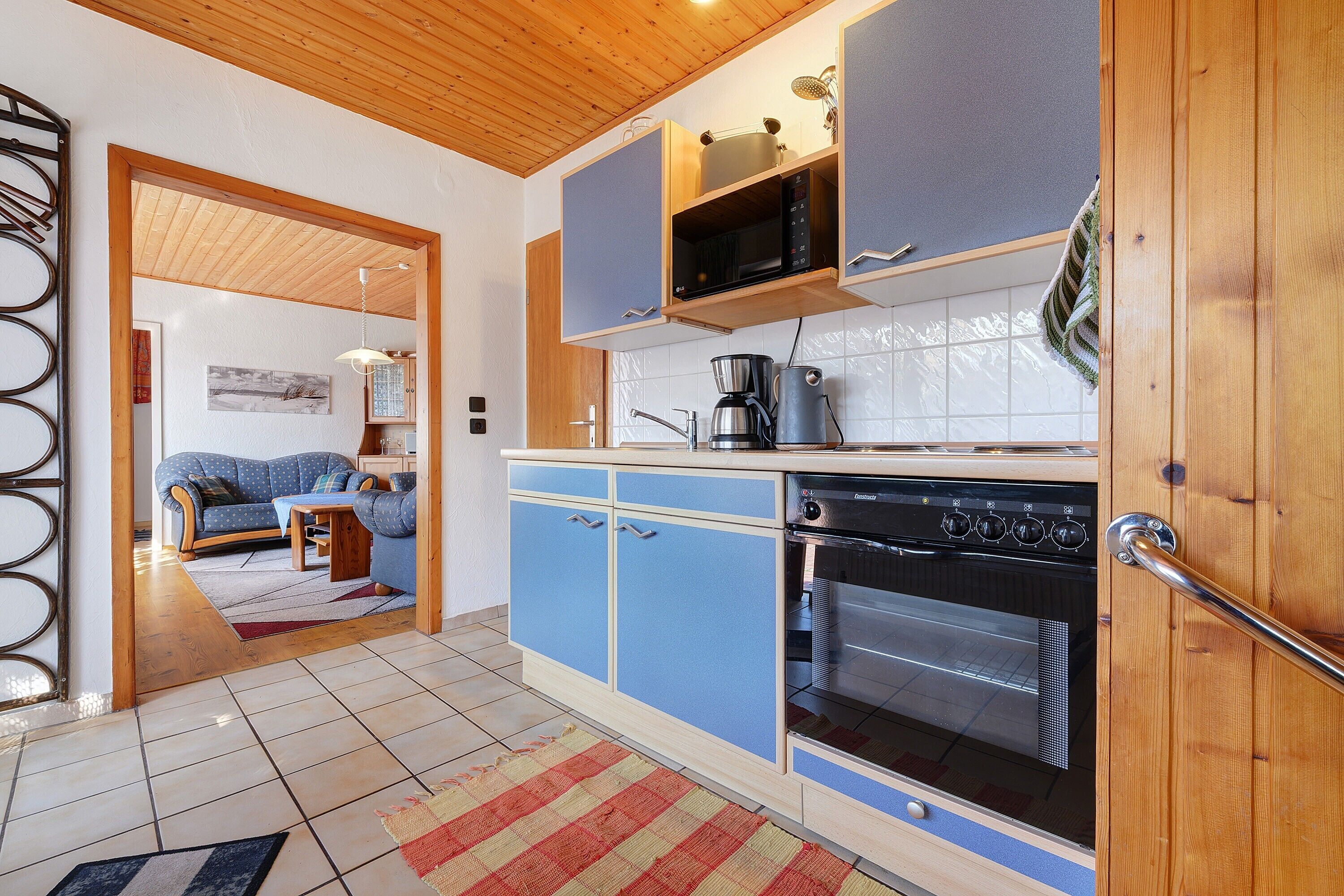 Una cocina compacta con gabinetes azules, una cafetera y un horno.