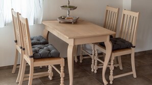 A dining area with a wooden table and chairs, a candle holder, and a window with curtains.