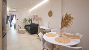 Een moderne woonkamer met een bank, een eettafel met stoelen, en een keuken met een koelkast.