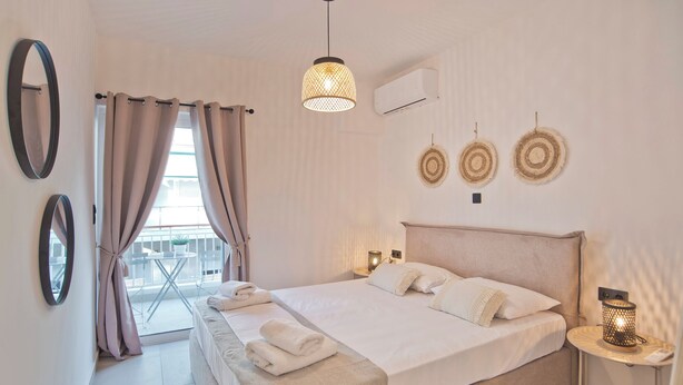 Een slaapkamer met een bed, nachtlampjes, een raam met gordijnen en wanddecoratie.