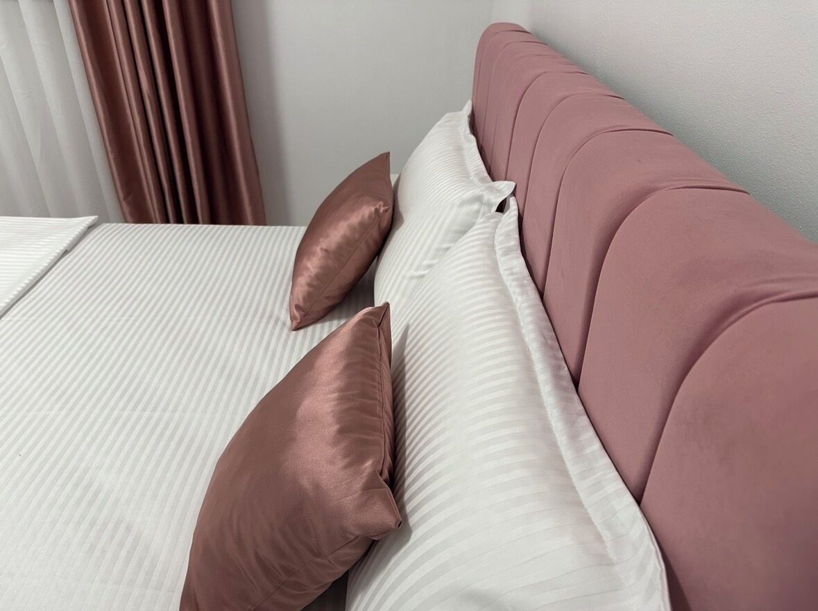 A bed with white bedding and two brown pillows.