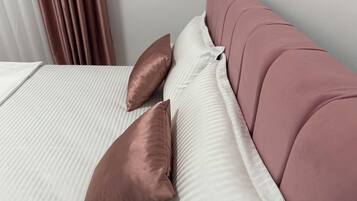 A bed with white bedding and two brown pillows.