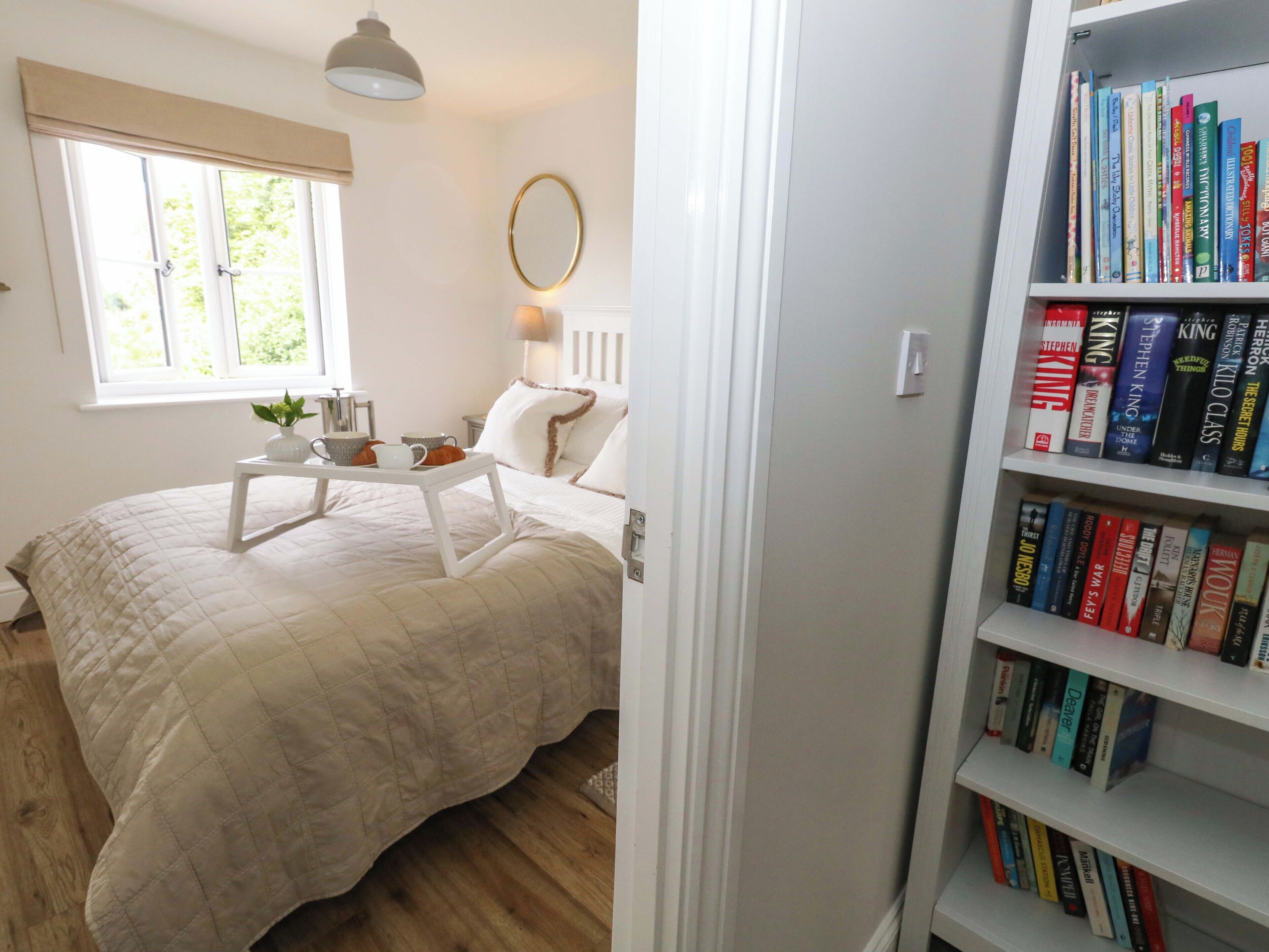 Ein Schlafzimmer mit einem Bett, einem Nachttisch und einem Bücherregal voller Bücher.