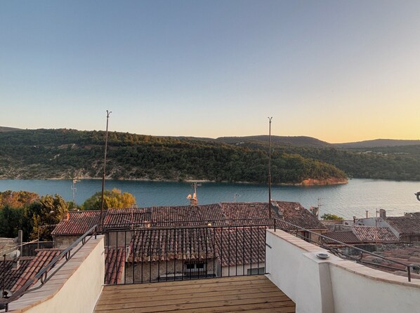 Terraço com telhados de azulejos com vista para um lago e colinas.
