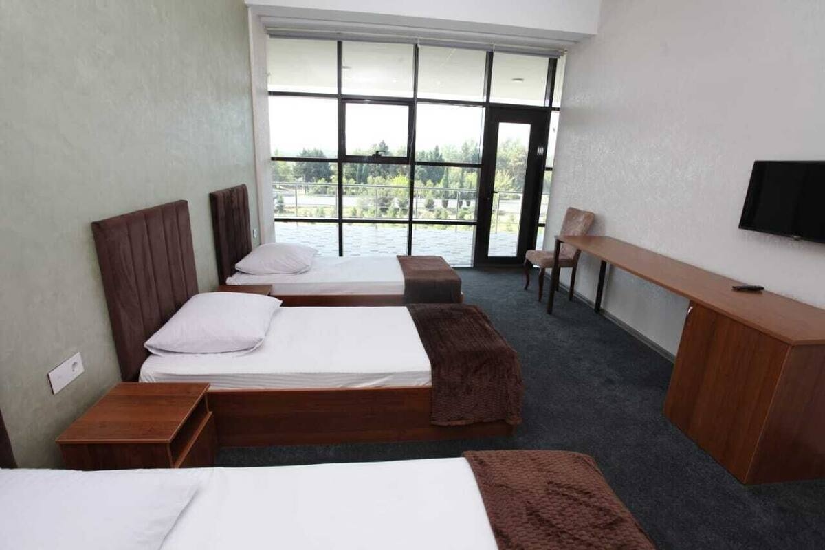 Ein Hotelzimmer mit zwei Betten, einem Schreibtisch und einem Fernseher.