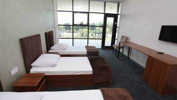 Ein Hotelzimmer mit zwei Betten, einem Schreibtisch und einem Fernseher.