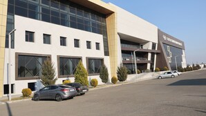 A modern building with large windows and a parking lot. - Arena Hotel Tartar (Tartar)