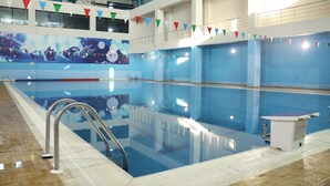 An indoor swimming pool with clear lanes, a lifeguard station, and colorful flags. - Arena Hotel Tartar (Tartar)