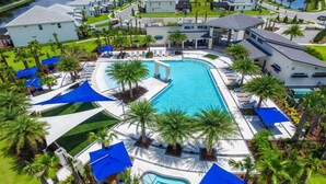 A resort with a central swimming pool, multiple lounge areas, and a well-maintained lawn.