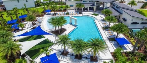 Un resort con piscina central, varias zonas de descanso y un césped bien cuidado.