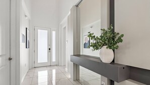 A modern hallway with a marble floor, a bench with a potted plant, and a door at the end.