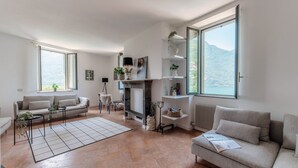 Un salon spacieux doté d’une cheminée, d’un canapé, d’une table basse et d’une grande fenêtre offrant une vue sur les montagnes.